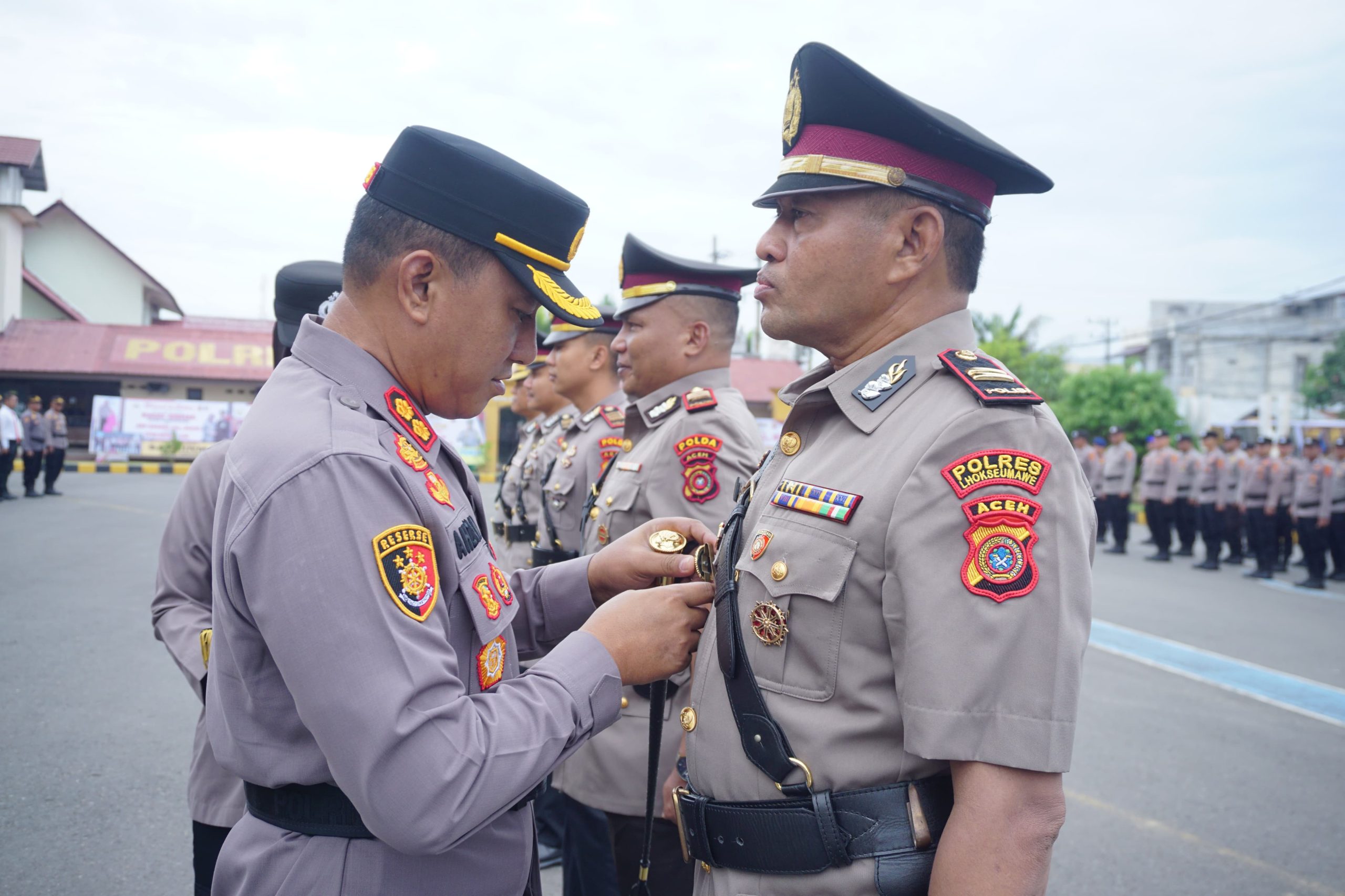 Kapolres Lhokseumawe AKBP Dr. Ahzan, S.H., S.I.K., M.S.M., M.H. memasangkan tanda jabatan kepada pejabat baru dalam upacara serah terima jabatan (sertijab) di Lapangan Satya Haprabu Polres Lhokseumawe, Senin (28/4/2025).