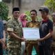 Bupati Pesisir Barat, Dedi Irawan (mengenakan baju motif loreng), secara simbolis menyerahkan bantuan sosial senilai Rp5.000.000 kepada Wayan Sudartono, salah satu korban kebakaran di Pekon Sumber Rejo, Kecamatan Bangkunat