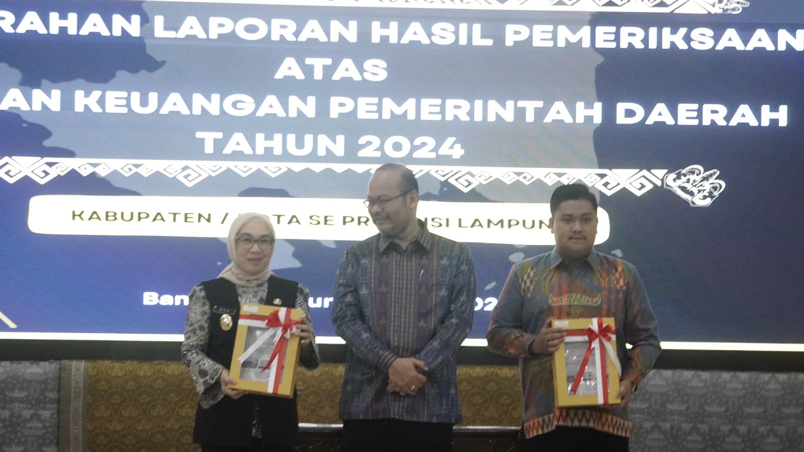 Plt. Bupati Way Kanan, Ayu Asalasiyah, S.Ked (kiri), menerima Laporan Hasil Pemeriksaan (LHP) atas LKPD Tahun Anggaran 2024 yang diserahkan langsung oleh Kepala BPK Perwakilan Provinsi Lampung, Nugroho Heru Wibowo (tengah), didampingi Ketua DPRD Way Kanan, Rial Kalbadi (kanan), dalam acara penyerahan LHP se-Provinsi Lampung di Auditorium BPK Lampung, Senin (26/5/2025).