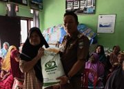 Peratin Kota Karang, Ridhoni, S.Pd., secara simbolis menyerahkan bantuan beras kepada salah satu warga penerima manfaat dalam kegiatan penyaluran bantuan pangan di Balai Pekon Kota Karang, Kecamatan Pesisir Utara, Selasa (29/7/2025).