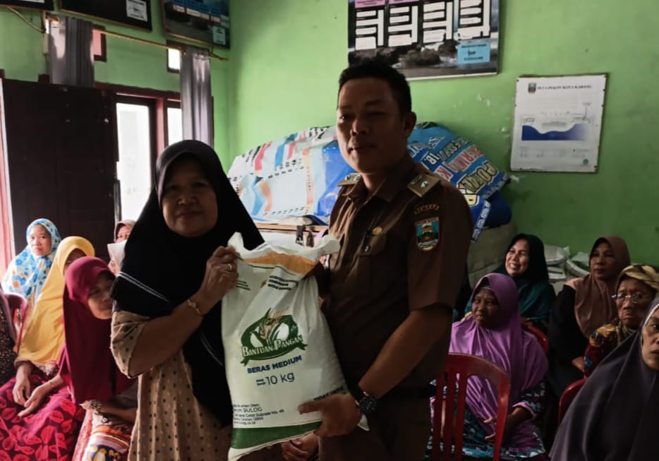 Peratin Kota Karang, Ridhoni, S.Pd., secara simbolis menyerahkan bantuan beras kepada salah satu warga penerima manfaat dalam kegiatan penyaluran bantuan pangan di Balai Pekon Kota Karang, Kecamatan Pesisir Utara, Selasa (29/7/2025).