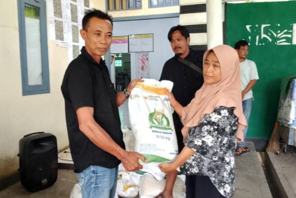 Peratin Pekon Biha, Rizkon Alhuda, S.H., menyerahkan bantuan beras kepada salah satu warga penerima manfaat di Balai Pekon Biha, Kecamatan Pesisir Selatan, Jumat (1/8/2025).